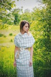 Jonge vrouw in geruite dressstay dichtbijgelegen een bloeiende boom royalty-vrije stock afbeeldingen Jonge vrouw in geruite dressstay dichtbijgelegen een bloeiende boom royalty-vrije stock afbeeldingen