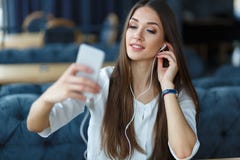Jonge vrouw het luisteren muziek die haar smartphone gebruiken Restaurantvergadering stock afbeeldingen Jonge vrouw het luisteren muziek die haar smartphone gebruiken Restaurantvergadering stock afbeeldingen