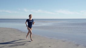 Jonge vrouw in zwempak die op overzees strand lopen Meisjesjogging langs oceaankust Vrouwelijke toerist die pret heeft Concept va stock video Jonge vrouw in zwempak die op overzees strand lopen Meisjesjogging langs oceaankust Vrouwelijke toerist die pret heeft Concept va stock video