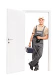 Jonge werknemer die toolbox houden en op deur leunen royalty-vrije stock foto Jonge werknemer die toolbox houden en op deur leunen royalty-vrije stock foto
