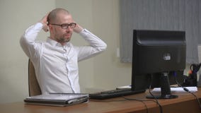 Jonge zakenman die in bureau werken, zittend bij bureau, die het computerscherm bekijken stock videobeelden Jonge zakenman die in bureau werken, zittend bij bureau, die het computerscherm bekijken stock videobeelden