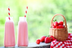 Jordgubbecoctail eller milkshake i en krus, korg med jordgubbar på en picknick, sund mat för frukost och mellanmål Royaltyfria Bilder Jordgubbecoctail eller milkshake i en krus, korg med jordgubbar på en picknick, sund mat för frukost och mellanmål Royaltyfria Bilder