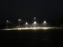 Jouant le tennis la nuit - le court de tennis s'est allumé la nuit photographie stock Jouant le tennis la nuit - le court de tennis s'est allumé la nuit photographie stock