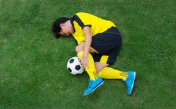 Joueur de football dans le mensonge jaune blessé sur le lancement image stock Joueur de football dans le mensonge jaune blessé sur le lancement image stock