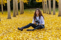 Jour d'automne d'Enjoying A de mod?le de brune dans le feuillage d'automne tenant une cam?ra professionnelle images libres de droits Jour d'automne d'Enjoying A de mod?le de brune dans le feuillage d'automne tenant une cam?ra professionnelle images libres de droits