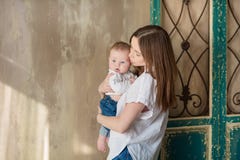 Jour de mères heureux Femme heureuse adorable avec le bébé posant dans les décorations modernes élégantes de studio Élément de co photo stock Jour de mères heureux Femme heureuse adorable avec le bébé posant dans les décorations modernes élégantes de studio Élément de co photo stock