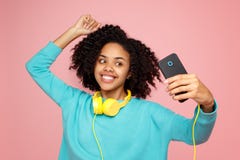 A jovem mulher afro-americano atrativa com sorriso brilhante vestida na roupa ocasional toma a imagem com smartphone sobre fotos de stock A jovem mulher afro-americano atrativa com sorriso brilhante vestida na roupa ocasional toma a imagem com smartphone sobre fotos de stock