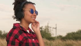 Jovem mulher afro-americano Biracial do adolescente da menina da raça misturada que escuta a música em seus telefone celular e fo video estoque Jovem mulher afro-americano Biracial do adolescente da menina da raça misturada que escuta a música em seus telefone celular e fo video estoque