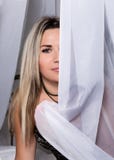 Jovem mulher bonita alegre que senta-se em uma cama atrás das cortinas e do sorriso fotos de stock Jovem mulher bonita alegre que senta-se em uma cama atrás das cortinas e do sorriso fotos de stock
