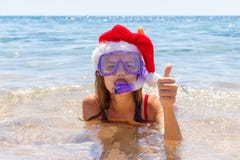 Jovem mulher bonita com mergulhar o equipamento e o chapéu do Natal na costa de mar imagens de stock Jovem mulher bonita com mergulhar o equipamento e o chapéu do Natal na costa de mar imagens de stock