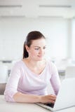 Jovem mulher bonita que trabalha em seu laptop imagem de stock Jovem mulher bonita que trabalha em seu laptop imagem de stock