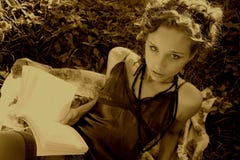 A jovem mulher bonita é Readng um livro no parque foto de stock royalty free A jovem mulher bonita é Readng um livro no parque foto de stock royalty free