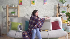 Jovem mulher congelada na sala de visitas e tomar sol ao lado dos calefatores elétricos filme Jovem mulher congelada na sala de visitas e tomar sol ao lado dos calefatores elétricos filme