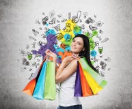 Jovem mulher de sorriso bonita com os sacos de compras coloridos das lojas extravagantes imagem de stock royalty free Jovem mulher de sorriso bonita com os sacos de compras coloridos das lojas extravagantes imagem de stock royalty free