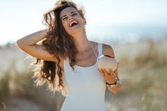 Jovem mulher feliz com o coco que ajusta o cabelo na costa do oceano fotografia de stock Jovem mulher feliz com o coco que ajusta o cabelo na costa do oceano fotografia de stock