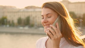 Jovem mulher feliz que relaxa fora Menina bonita que fala em seu smartphone Sol do verão que brilha filme Jovem mulher feliz que relaxa fora Menina bonita que fala em seu smartphone Sol do verão que brilha filme