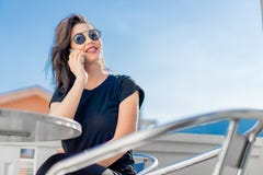 Jovem mulher ? moda que senta-se fora no balc?o e que fala pelo telefone celular fotos de stock Jovem mulher ? moda que senta-se fora no balc?o e que fala pelo telefone celular fotos de stock