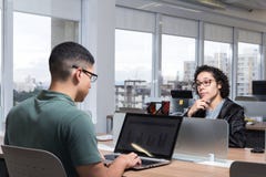A jovem mulher olha o colega de trabalho na parte dianteira fotografia de stock A jovem mulher olha o colega de trabalho na parte dianteira fotografia de stock