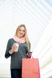 Jovem mulher que anda no shopping que faz uma chamada com smartpho fotografia de stock Jovem mulher que anda no shopping que faz uma chamada com smartpho fotografia de stock