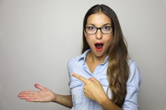 Jovem mulher que mostra o produto com a palma aberta da mão e que aponta o dedo Expressão entusiasmado nos vidros vestindo da mul fotografia de stock royalty free Jovem mulher que mostra o produto com a palma aberta da mão e que aponta o dedo Expressão entusiasmado nos vidros vestindo da mul fotografia de stock royalty free