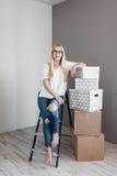 Jovem mulher que move-se em sua casa nova e que faz uma reforma da casa, está sentando-se na escada com muitas caixas de cartão foto de stock Jovem mulher que move-se em sua casa nova e que faz uma reforma da casa, está sentando-se na escada com muitas caixas de cartão foto de stock