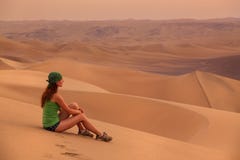 Jovem mulher que senta-se na areia em um deserto perto de Huacachina, registro do AIC fotos de stock royalty free Jovem mulher que senta-se na areia em um deserto perto de Huacachina, registro do AIC fotos de stock royalty free