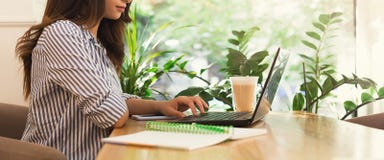 Jovem mulher que usa o portátil no café e bebendo o café foto de stock Jovem mulher que usa o portátil no café e bebendo o café foto de stock