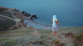 A jovem senhora delgada em um lenço e em um vestido vai nas montanhas ao mar video estoque A jovem senhora delgada em um lenço e em um vestido vai nas montanhas ao mar video estoque
