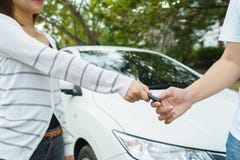 Jovens mulheres que dão um carro chave ao homem novo na fonte de carro foto de stock Jovens mulheres que dão um carro chave ao homem novo na fonte de carro foto de stock
