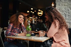 Jovens mulheres que sentam-se em uma fala do restaurante foto de stock Jovens mulheres que sentam-se em uma fala do restaurante foto de stock