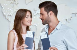 Joyful couple looking to each other and holding passport with flying tickets royalty free stock photos Joyful couple looking to each other and holding passport with flying tickets royalty free stock photos