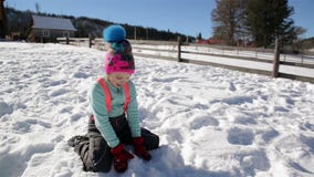 Joyous Meisje heeft ter plaatse Pret in de Sneeuwzitting en werpt Sneeuwvlokken in de Lucht Zonnige de winterdag stock video Joyous Meisje heeft ter plaatse Pret in de Sneeuwzitting en werpt Sneeuwvlokken in de Lucht Zonnige de winterdag stock video