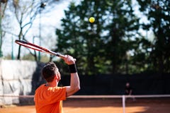 Jugador de tenis en la porción anaranjada con la bola en mediados de-aire y otro fotografía de archivo Jugador de tenis en la porción anaranjada con la bola en mediados de-aire y otro fotografía de archivo