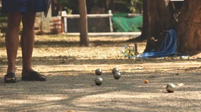 Jugando Petanque en el parque - bolas de metal y bola de madera anaranjada en yarda de la roca con un hombre que se coloca en el fotos de archivo libres de regalías Jugando Petanque en el parque - bolas de metal y bola de madera anaranjada en yarda de la roca con un hombre que se coloca en el fotos de archivo libres de regalías