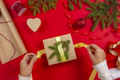 Julgåvainpackning Kvinna` s räcker emballagejulklappasken på röd tabellbakgrund fotografering för bildbyråer Julgåvainpackning Kvinna` s räcker emballagejulklappasken på röd tabellbakgrund fotografering för bildbyråer