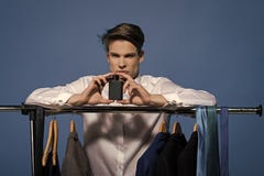 Junge angetrieben Fragegesichtsjungen Bemannen Sie Griffparfüm in der Garderobe auf blauem Hintergrund lizenzfreie stockbilder Junge angetrieben Fragegesichtsjungen Bemannen Sie Griffparfüm in der Garderobe auf blauem Hintergrund lizenzfreie stockbilder