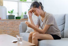 Junge Asiatinnen auf dem Sofa, das ihre Augen schließt, leiden unter Kopfschmerzen und haben etwas Fieber lizenzfreies stockfoto Junge Asiatinnen auf dem Sofa, das ihre Augen schließt, leiden unter Kopfschmerzen und haben etwas Fieber lizenzfreies stockfoto