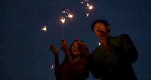Junge asiatische Paare, die zusammen Feuerwerke an der Dachspitze spielen Junge asiatische Paare, die zusammen Feuerwerke an der Dachspitze spielen