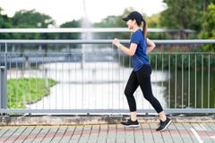 Junge attraktive asiatische Läuferfrau, die öffentlich am Natur-Stadtpark der Bürgersteigsweise mit dem Seewasser-Ansichttragen b stockfoto Junge attraktive asiatische Läuferfrau, die öffentlich am Natur-Stadtpark der Bürgersteigsweise mit dem Seewasser-Ansichttragen b stockfoto