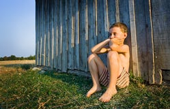 Junge, der nahe Wand sitzt stockfotografie Junge, der nahe Wand sitzt stockfotografie