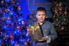 Junge in einem Denimhemd mit einem Geschenk in den Händen lizenzfreie stockbilder Junge in einem Denimhemd mit einem Geschenk in den Händen lizenzfreie stockbilder