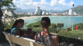 Junge Familie, die auf der Bank auf dem Hügel übersieht das Meer stillsteht stock video Junge Familie, die auf der Bank auf dem Hügel übersieht das Meer stillsteht stock video