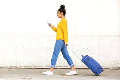 Junge Frau, die mit Reisetasche geht und Handy verwendet lizenzfreie stockfotografie Junge Frau, die mit Reisetasche geht und Handy verwendet lizenzfreie stockfotografie
