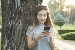 Junge Frau, die Smartphone im Park verwendet lizenzfreie stockfotografie Junge Frau, die Smartphone im Park verwendet lizenzfreie stockfotografie