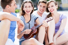 Junge Frau, die Ukulele für Freunde spielt stockfotografie Junge Frau, die Ukulele für Freunde spielt stockfotografie