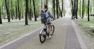 Junge Frau mit einem Rucksack fährt in den Park rad stock video footage Junge Frau mit einem Rucksack fährt in den Park rad stock video footage