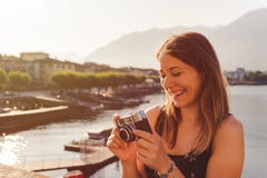 Junge Frau unter Verwendung einer Weinlesekamera vor der Seepromenade in Ascona lizenzfreie stockbilder Junge Frau unter Verwendung einer Weinlesekamera vor der Seepromenade in Ascona lizenzfreie stockbilder