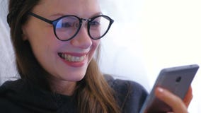 Junge glückliche brunette Frau in den Gläsern schreibt eine Mitteilung an einem Handy stock video footage Junge glückliche brunette Frau in den Gläsern schreibt eine Mitteilung an einem Handy stock video footage