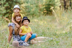 Junge glückliche Großmutter mit zwei kleinen Enkelkindern, die an sitzen lizenzfreie stockfotos Junge glückliche Großmutter mit zwei kleinen Enkelkindern, die an sitzen lizenzfreie stockfotos