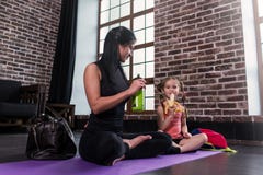 Junge kaukasische Frau und glückliches ein Mädchenkind, das nach dem Yogatraining sitzt auf Matte mit den Beinen sich entspannt, lizenzfreie stockbilder Junge kaukasische Frau und glückliches ein Mädchenkind, das nach dem Yogatraining sitzt auf Matte mit den Beinen sich entspannt, lizenzfreie stockbilder